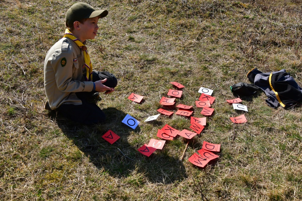 Malý skaut skládá z papírových písmen slova.