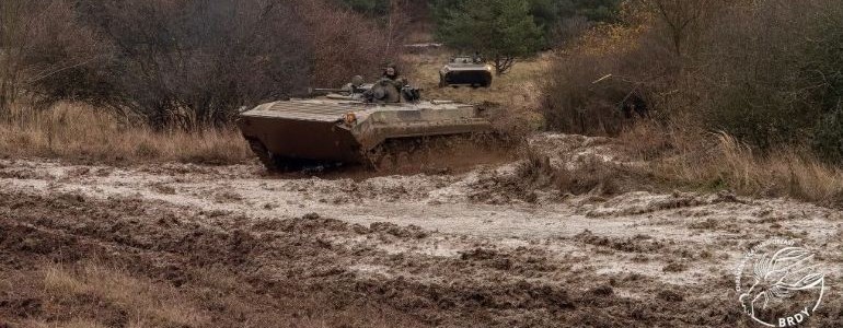 Bojové vozidlo pěchoty projíždí řídkým blátem na vojenském cvičišti.